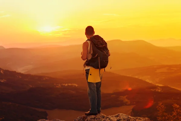 Um tipo nas montanhas ao pôr-do-sol. o conceito de liberdade — Fotografia de Stock