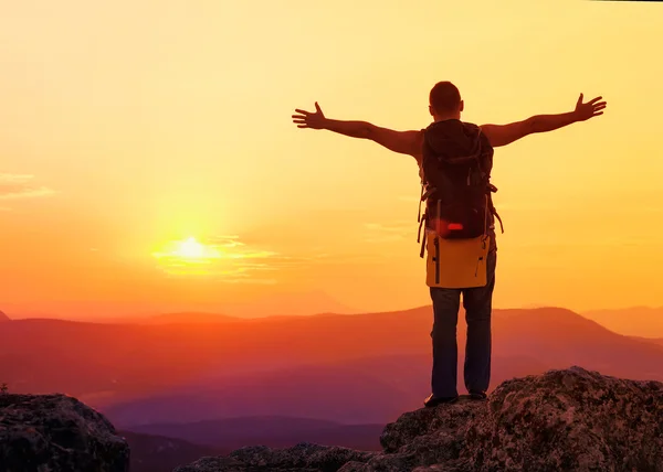 Kerel in de bergen bij zonsondergang. het concept van vrijheid — Stockfoto