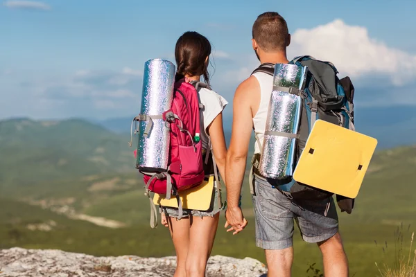 Caminhantes com mochilas desfrutando de vista para o vale a partir do topo de uma montanha — Fotografia de Stock