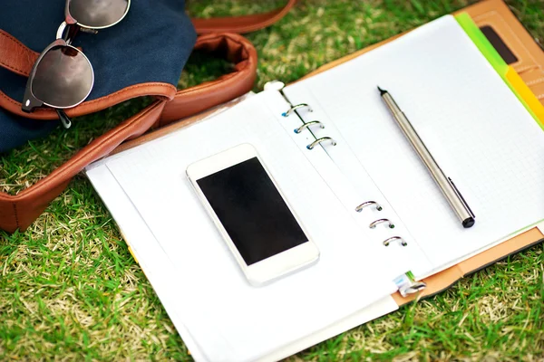 Modern digital notebook  with mobile smartphone on green grass — Stock Photo, Image