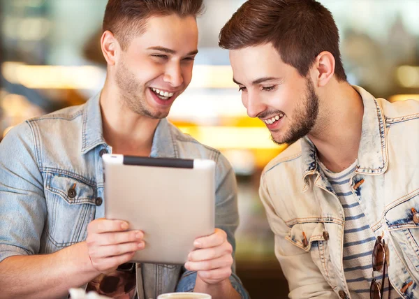 Two young students using tablet computer in cafe — Stock Photo, Image