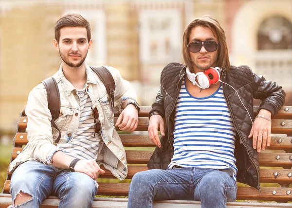 Two young fashion women in the park listening to music — Stock Photo, Image