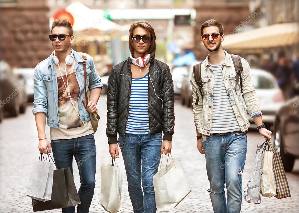 Three Young male fashion metraseksuals shop. Men shopping walk.