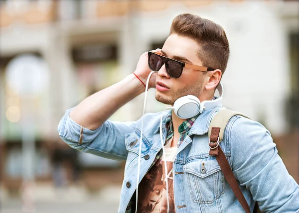 Handsome fashion man smiling and listening to music on the grass — Stock Photo, Image
