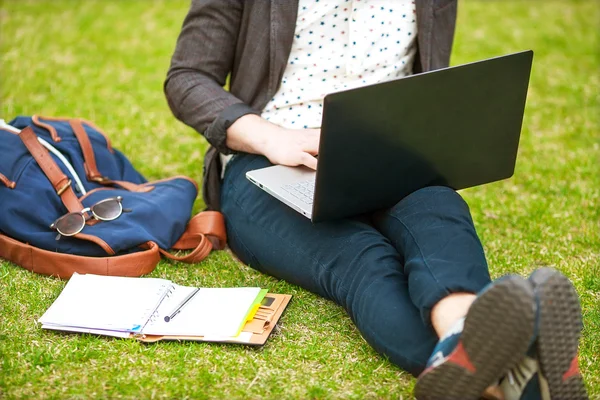 年轻人在草地上使用他的笔记本电脑 — 图库照片