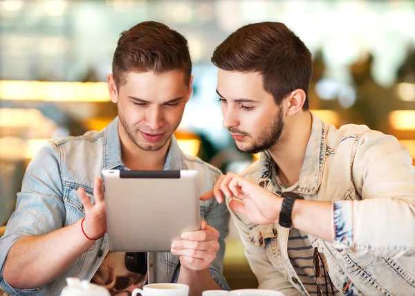 Two young students using tablet computer in cafe — Stock Photo, Image