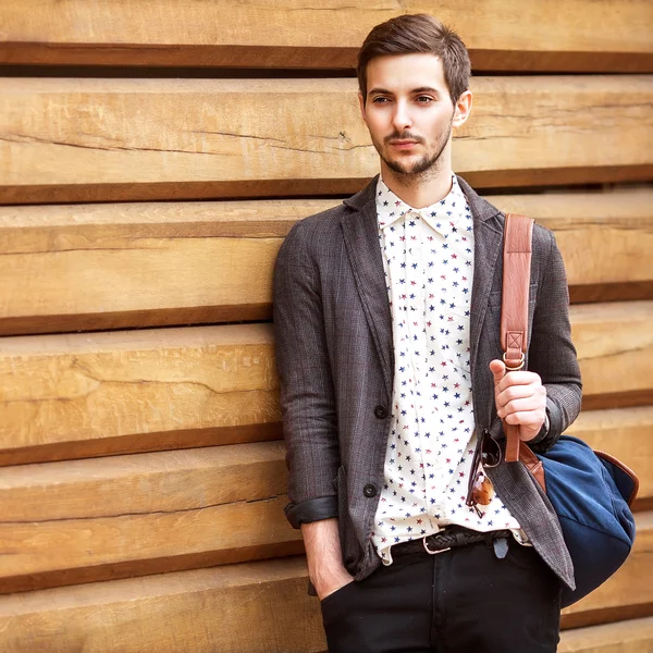 Portret van jonge mooie modieuze man tegen houten muur. — Stockfoto