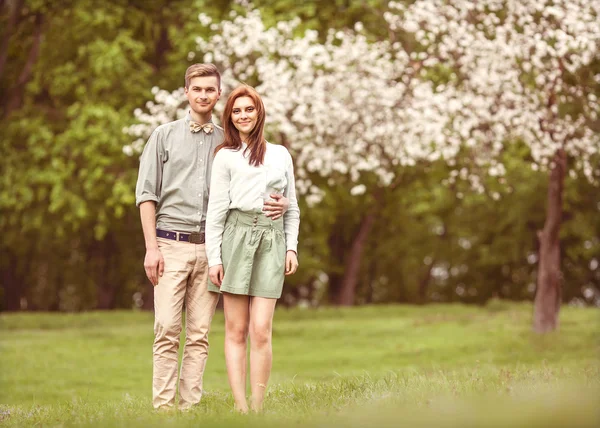 Pareja enamorada en floreciente jardín de manzanos, sonriendo —  Fotos de Stock