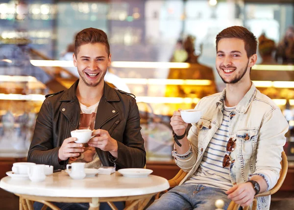 Two young hipster guy sitting in a cafe chatting and drinking coffee smiling — Stock Photo, Image