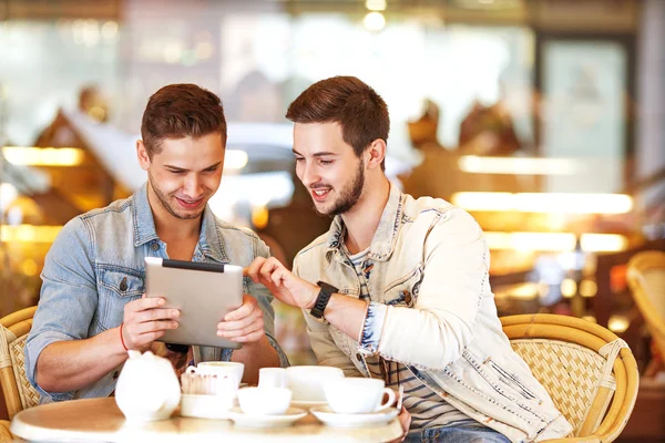 Two young students using tablet computer in cafe — Stock Photo, Image