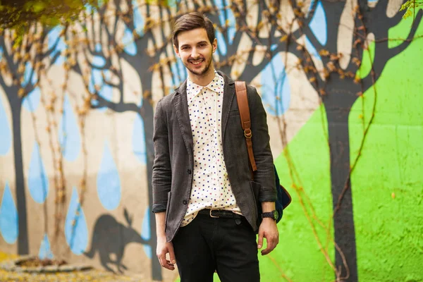 Aantrekkelijke jonge mannelijke model poseren op groene muur buitenshuis — Stockfoto