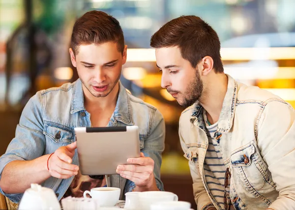 Dos jóvenes estudiantes que usan tableta en la cafetería —  Fotos de Stock