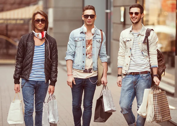 Tres hombres jóvenes metraseksuals moda tienda de compras a pie — Foto de Stock