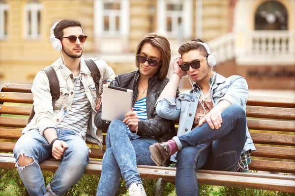 Fashion boys sit in the park listening to music — Stock Photo, Image