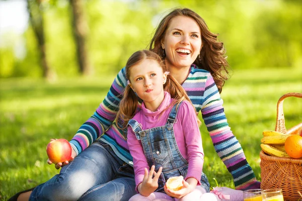 Madre e hija al aire libre en un picnic comer manzana — Foto de Stock