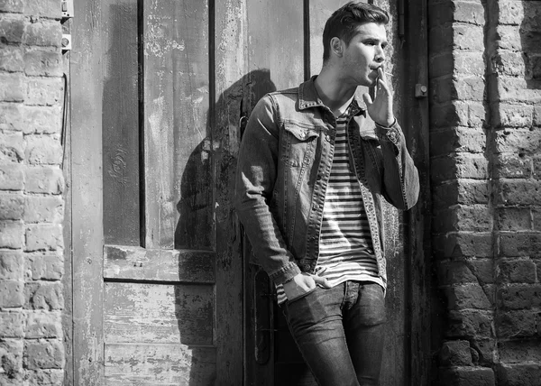 Hipster style guy. Fashion man standing near a wooden door — Stock Photo, Image