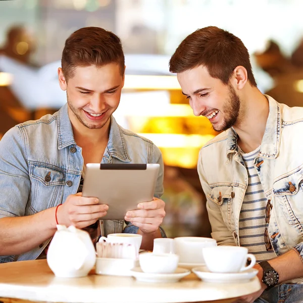 Nuori hipsteri kaveri istuu kahvilassa juttelemassa ja juomassa kahvia — kuvapankkivalokuva