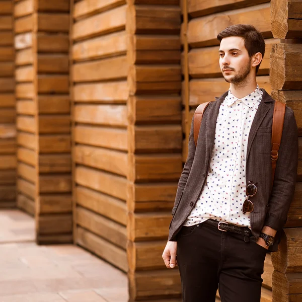 Portret van jonge mooie modieuze man tegen houten muur. — Stockfoto