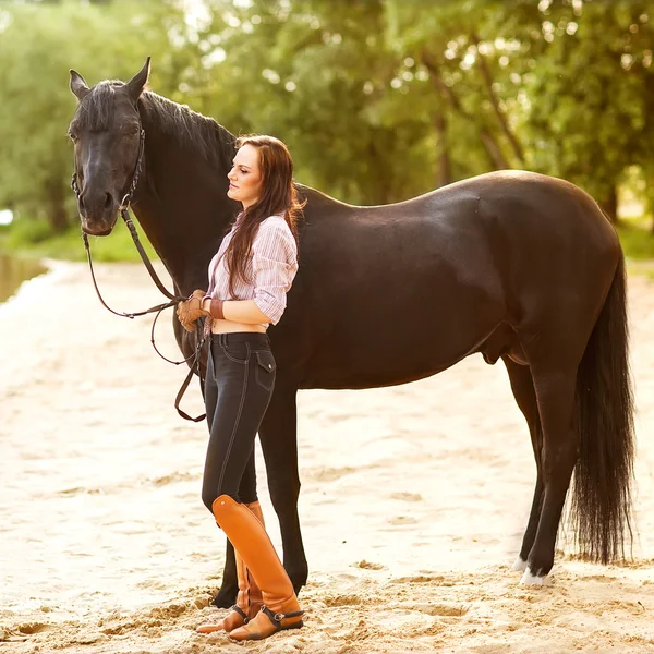 Giovane donna con un cavallo in parco vicino al fiume — Foto Stock