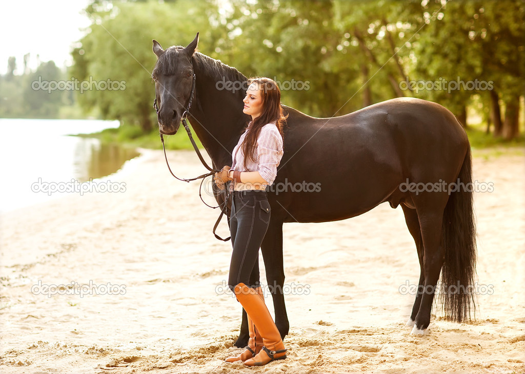 Young woman with a horse in park near the river