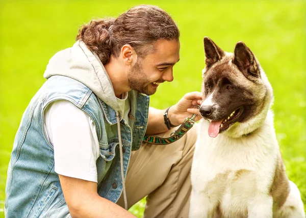 El hombre y el perro Akita Inu pasean por el parque . — Foto de Stock