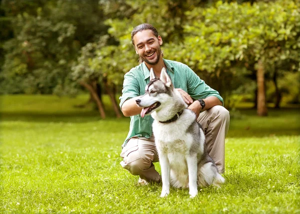 İnsan ve Husky köpeği parkta yürüyor..