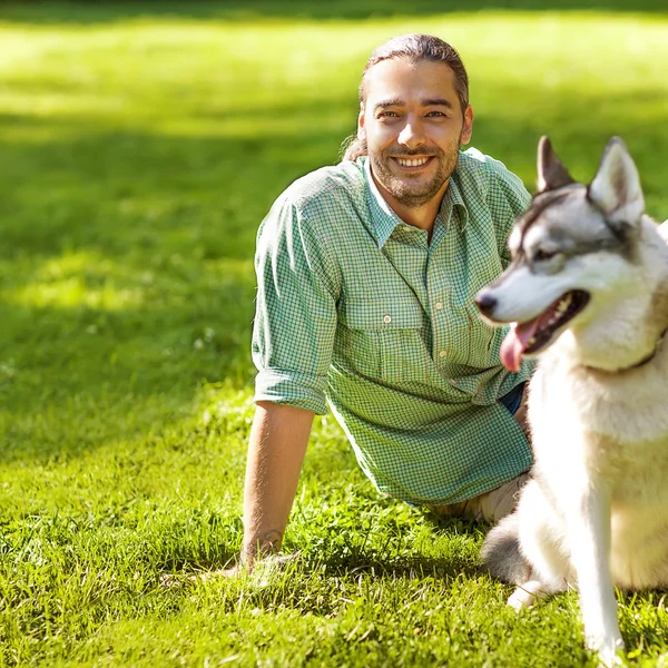 Hombre y perro Husky pasear en el parque . —  Fotos de Stock