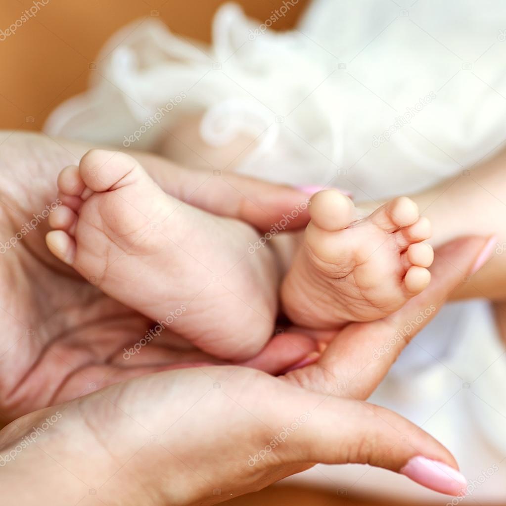 Baby feet cupped into mothers hands.