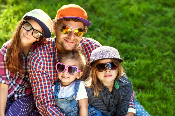Його три дочки лежать на траві в сонцезахисних окулярах щасливі . — стокове фото