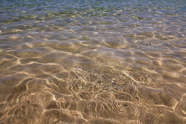 Fondo marino fondo marino con resplandor solar. Vista a través del agua del fondo arenoso — Foto de Stock