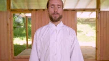 Pratik yapmak için beyaz sakallı beyaz adam salonun ahşap odasında qigong çalışıyor. Enerji uygulamasının modern gelenekleri