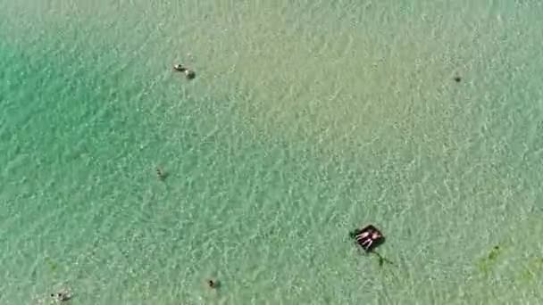Veduta aerea di acque poco profonde vicino alla riva del mare dove le persone fanno il bagno e nuotano su materassi — Video Stock