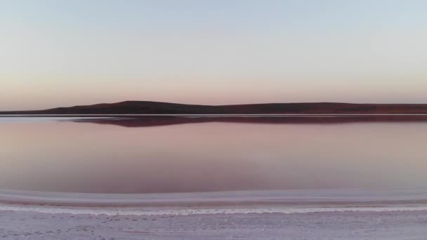 Letecký pohled Směrem dolů se nakláněl nízko položeným růžovým solným jezerem. Filmová zrna. Dobrý večer. Přírodní zdravá růžová sůl — Stock video