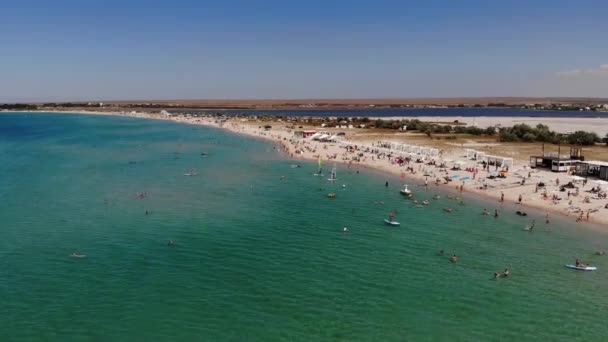 Widok z lotu ptaka na plażę turystyczną z ludźmi odpoczywającymi. Piaszczysta plaża nadmorskiego kurortu w słoneczny dzień. Rekreacja na wybrzeżu oceanu — Wideo stockowe