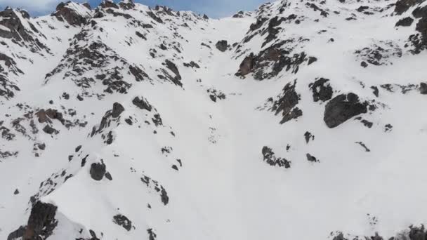 Snötäckt vild stenig sluttning högt uppe i bergen. Brant couloir för extrem skidåkning. Freeride plats för avancerade ryttare. Flygbild — Stockvideo