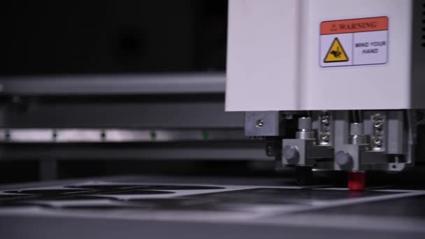 Industrieel Een close-up van een industriële plotter snijdt een sjabloon op een kartonnen verpakking voor producten. real-time ondiepe scherptediepte. Live camera — Stockvideo