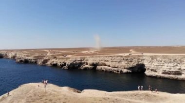 Tozlu bir şeytan, kumlu bir kıyıdaki bir kasırga kuru bir çalılığın içinden şiddetle geçer. Bozkır manzaralı tozlu arazi turistleri. Doğal fenomen