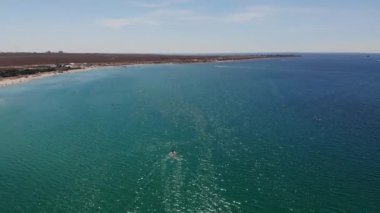 İnsanların dinlendiği bir turist plajının havadan görüntüsü. Güneşli bir günde, deniz kıyısındaki tatil beldesinin kumsalı. Okyanus kıyısında eğlence.