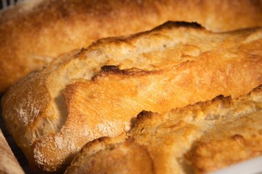 Ekmeğe yakın çekim. Fırının ahşap raflarında altın kabuklu taze pişmiş ekmek. Kırsal ekmek çeşitleri olan bir Alman zanaatkar fırınının içeriği.