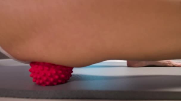 Nahaufnahme des weiblichen Oberschenkels in Unterwäsche junge kaukasische Frau macht myofasziale Selbstmassage ihres Oberschenkels und Gesäßes mit einem Massageball auf einer Massagematte. 4k-Auflösung — Stockvideo