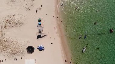 İnsanların dinlendiği bir turist plajının üst hava manzarası. Güneşli bir günde, deniz kıyısındaki tatil beldesinin kumsalı. Okyanus kıyısında eğlence.