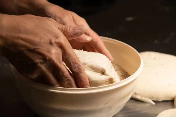 Primer plano de un panadero manos femeninas sumergiendo la masa en un tazón de semillas y cereales antes de hornear pan artesanal en una panadería casera — Foto de Stock