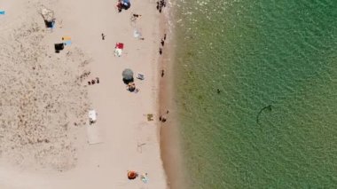 İnsanların dinlendiği bir turist plajının üst hava manzarası. Güneşli bir günde, deniz kıyısındaki tatil beldesinin kumsalı. Okyanus kıyısında eğlence.
