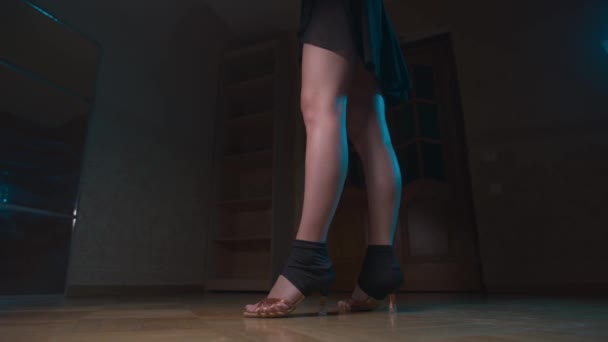 Крупным планом разогревают ноги молодой танцовщицы в бальной одежде и профессиональной обуви в темной комнате — стоковое видео
