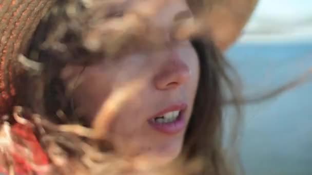 Närbild Slow motion ansikte härlig kaukasiska ung kvinna ur fokus. Vinden smeker och rynkar hennes hår. Fokusera på håret. Mot bakgrund av havshorisonten. — Stockvideo