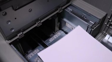 Erkek işadamı bir yazıcıya yazdırmak için bir paket beyaz kağıt yüklüyor.