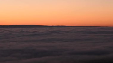 Sinematik 4K. Bulutların üstünde gün batımından sonra zaman geçiyor. Sis denizi katmanlardan oluşur. Bulutların üstünde sona erdi. Düz yüzey. Skyline kırmızı alacakaranlık arkaplan videosu