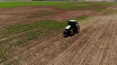 Çim biçme makinesi olan bir traktörün hava görüntüsü boş bir tarladaki çimleri biçer. Yıl boyunca saha hazırlığı ve bakımı