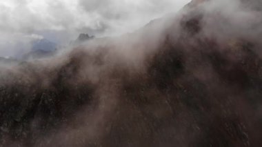 Dağlarda bulutların hareketinin akşam vakti hızlandırılması. Dağ tepeleri ve tepelerin üzerinden taşan bulutlar. Hava görüntüsü. İklim değişikliği. Küresel sıcaklık