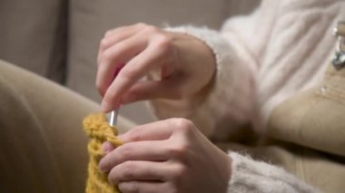 Örgü ören beyaz bir kızın genç kadın ellerine yakın çekim, nasıl düzgün örüleceğini gösteriyor. Yüzeyin derinliği. yüksek dinamik aralık.